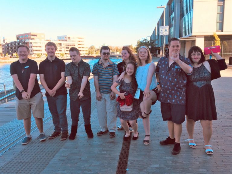 a group of people with down syndrome in front of a river.