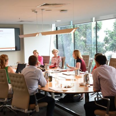 A board meting with people sitting around a meeting table