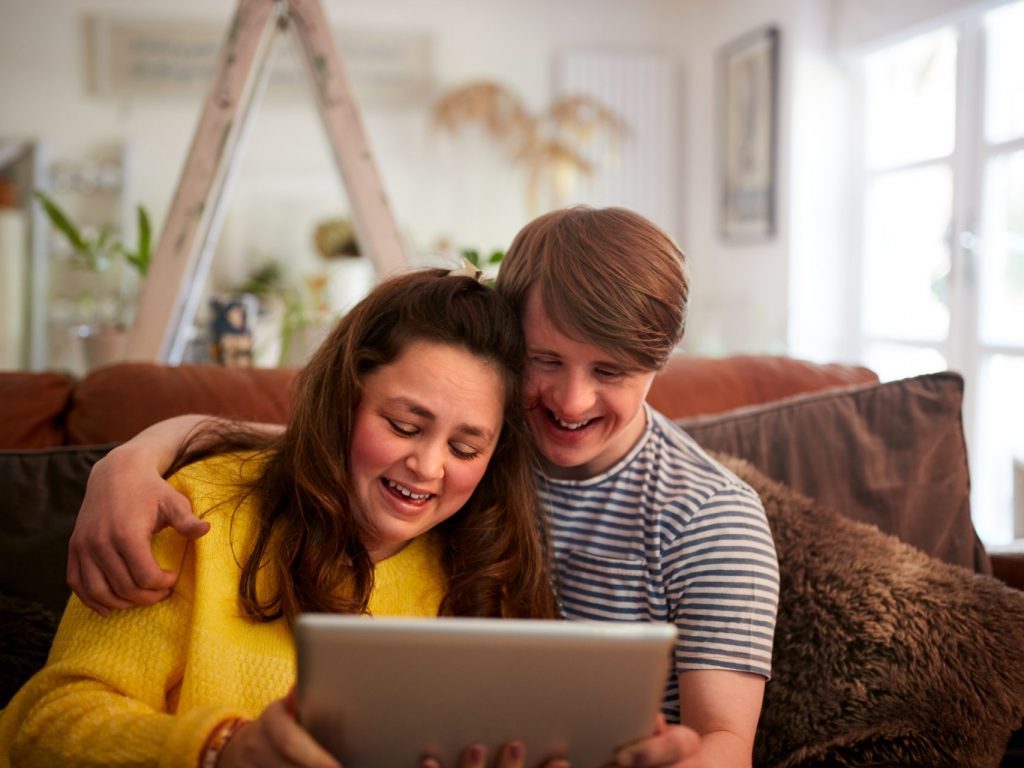 two young adults look at a tablet device together