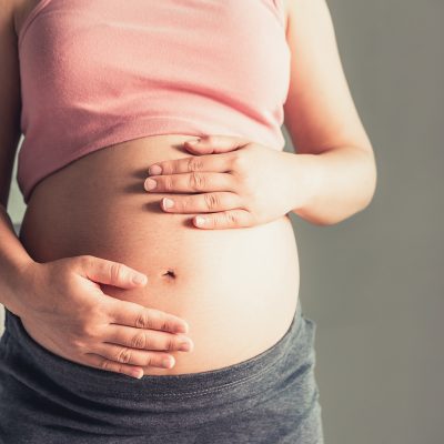 Pregnant woman with hands on her stomach.