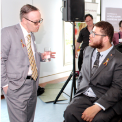 A man stands and speaks to a man in a wheelchair