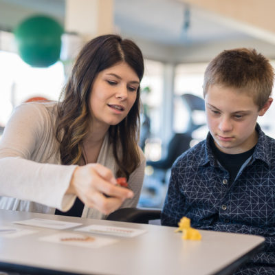 A woman teaching a school aged boy in a classroom