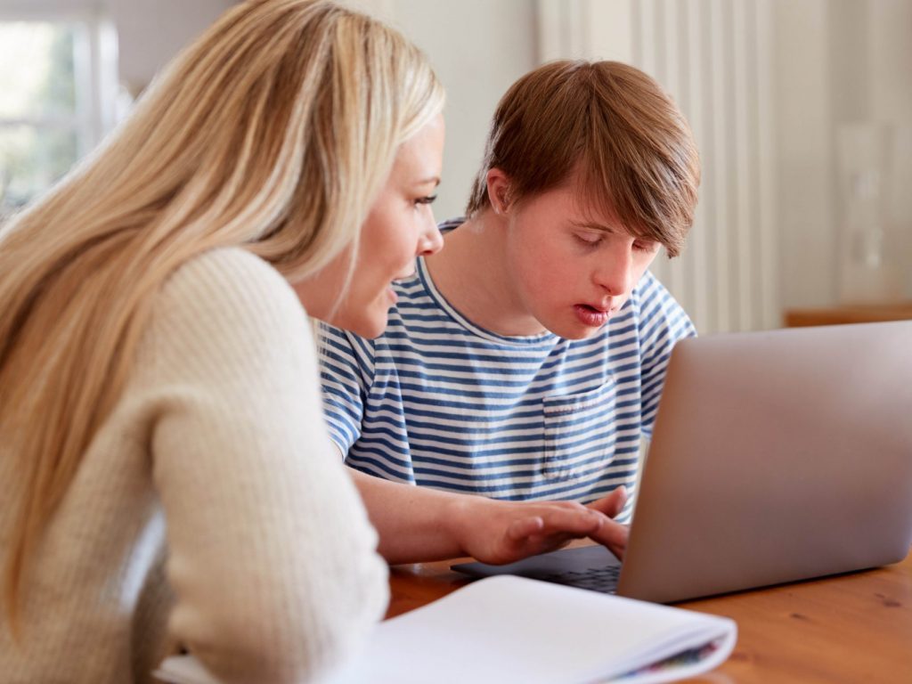 A woman and a young man look at a computer together