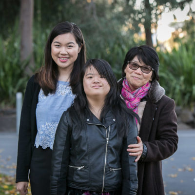 A young woman stands outdoors with her family